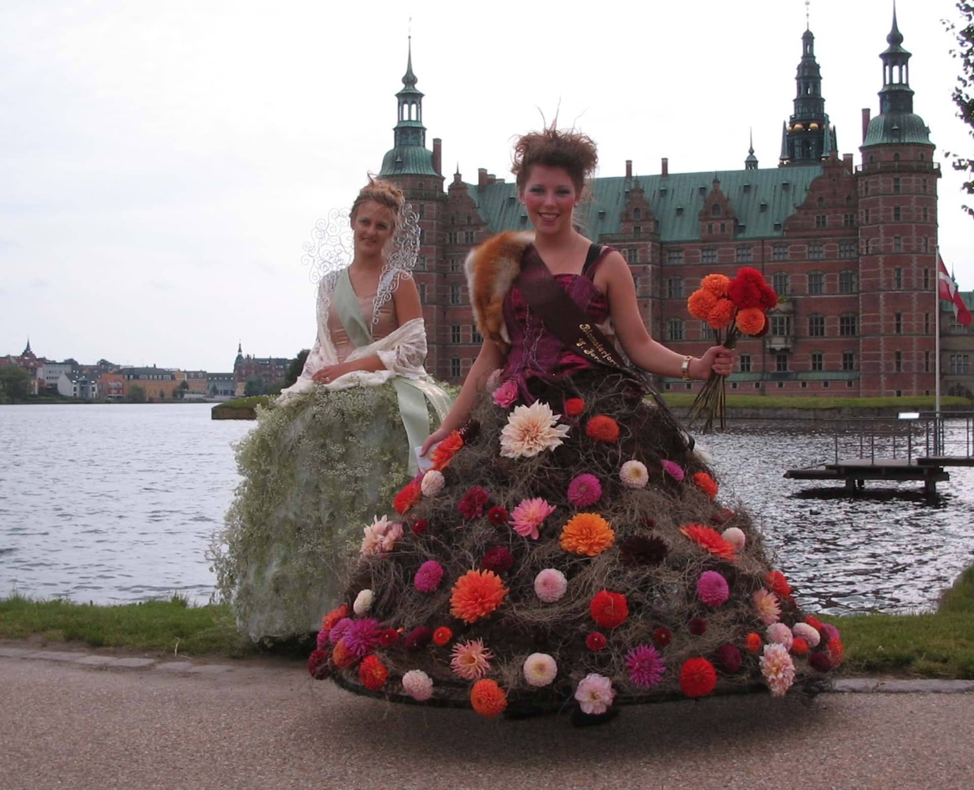 Unge kvinder i blomsterkjoler poserer foran Kronborg Slot